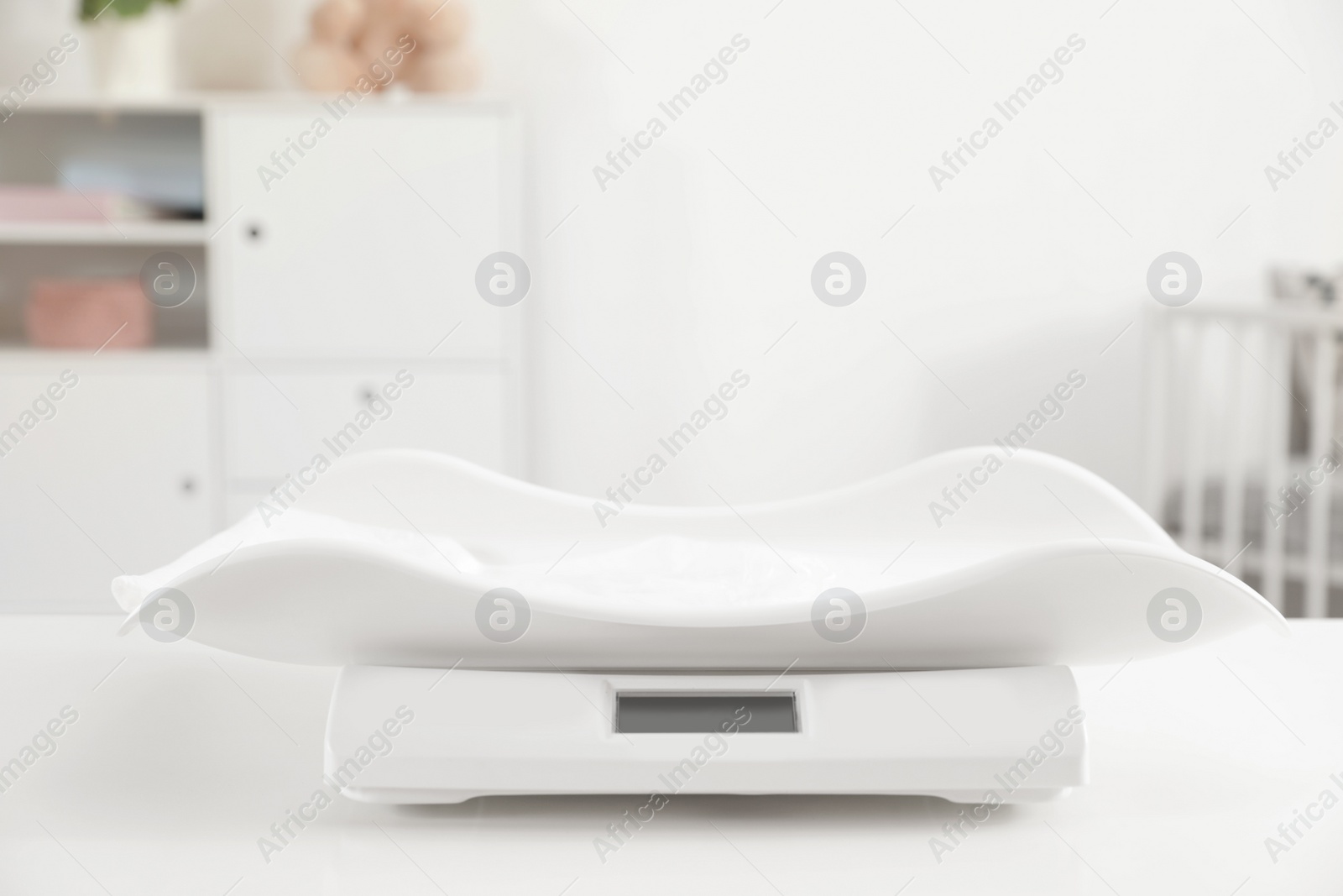 Photo of Modern digital baby scales on table in room. Space for text