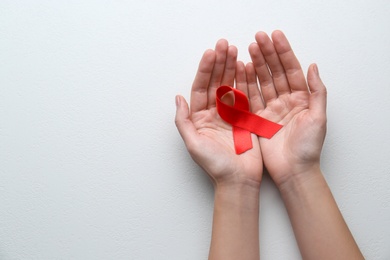 Photo of Woman holding red awareness ribbon on white background, top view with space for text. World AIDS disease day