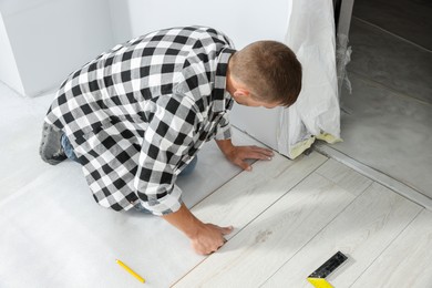 Photo of Professional worker installing new laminate flooring indoors