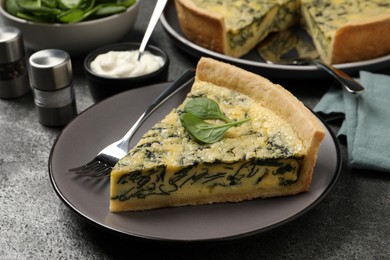 Piece of delicious spinach pie served on grey table, closeup