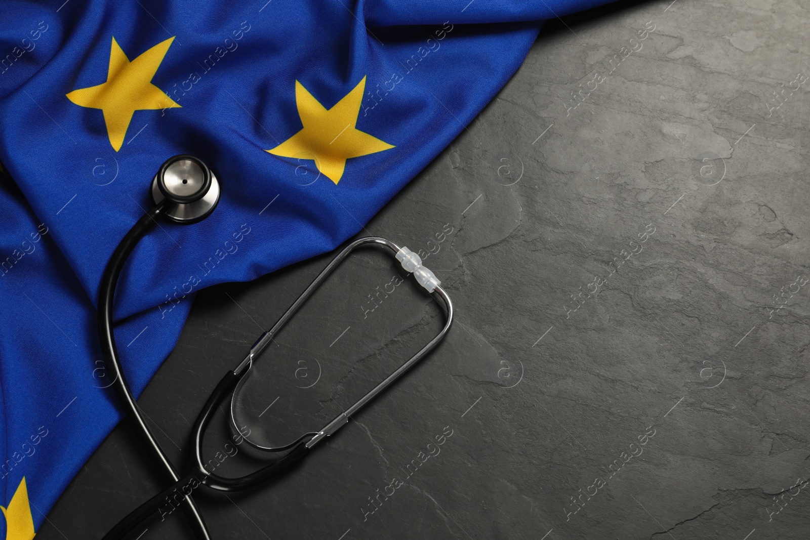 Photo of Stethoscope and flag of European Union on black table, flat lay Space for text