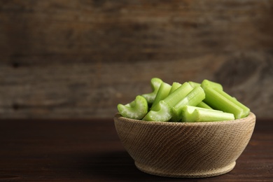 Cut celery in bowl on wooden table. Space for text