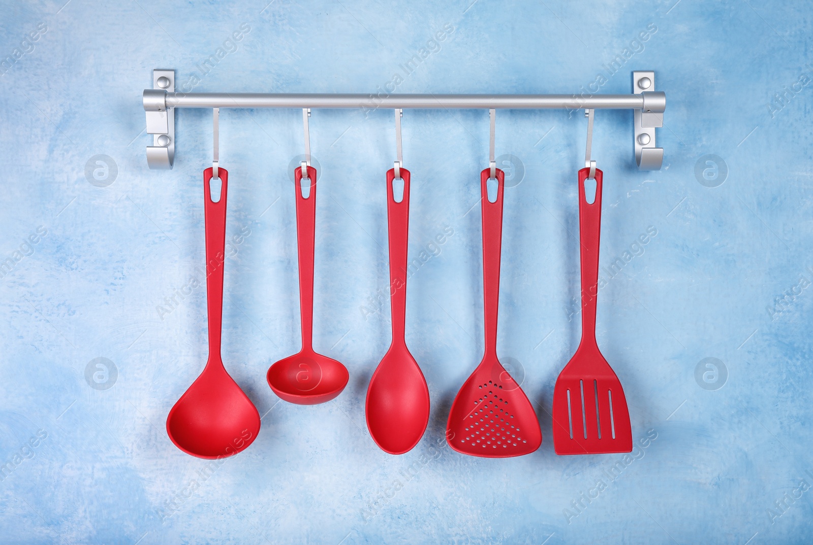 Photo of Rack with kitchen utensils hanging on light blue wall