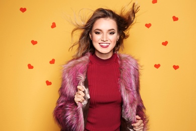 Photo of Beautiful young woman in fur coat posing on color background