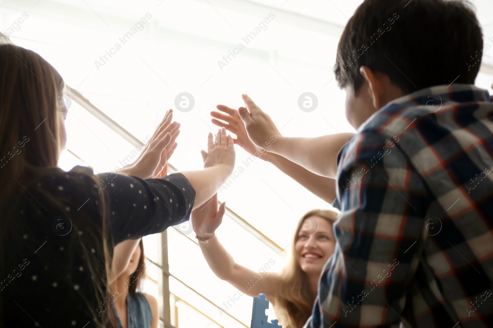 Photo of People putting hands together indoors. Unity concept