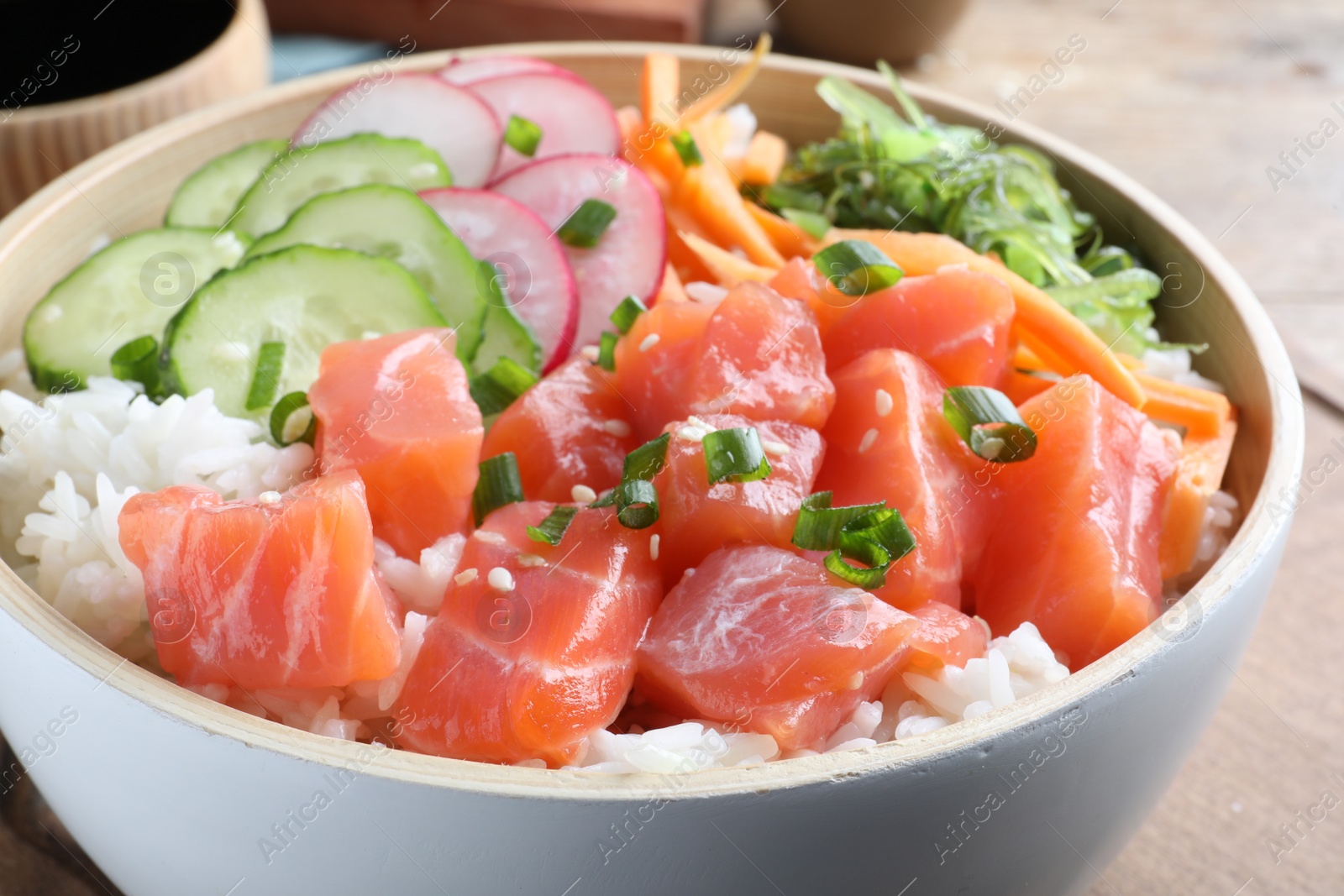 Photo of Delicious poke bowl with salmon and vegetables on table, closeup