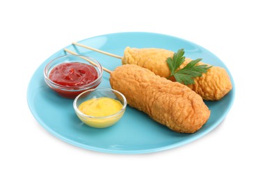 Photo of Delicious deep fried corn dogs with parsley and sauces on white background