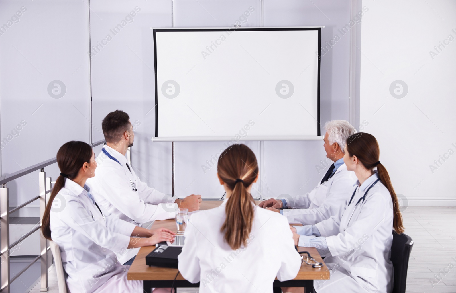 Photo of Team of doctors using video projector during conference indoors