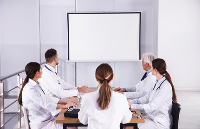 Team of doctors using video projector during conference indoors