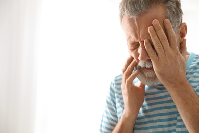 Photo of Mature man suffering from strong tooth pain on light background, space for text