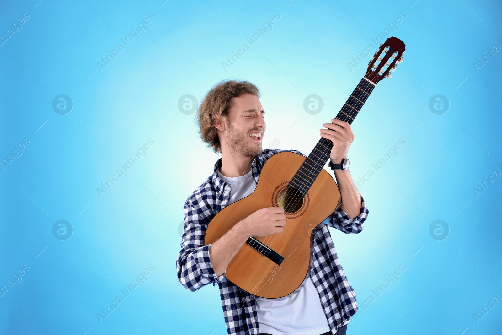 Photo of Young man playing acoustic guitar on color background
