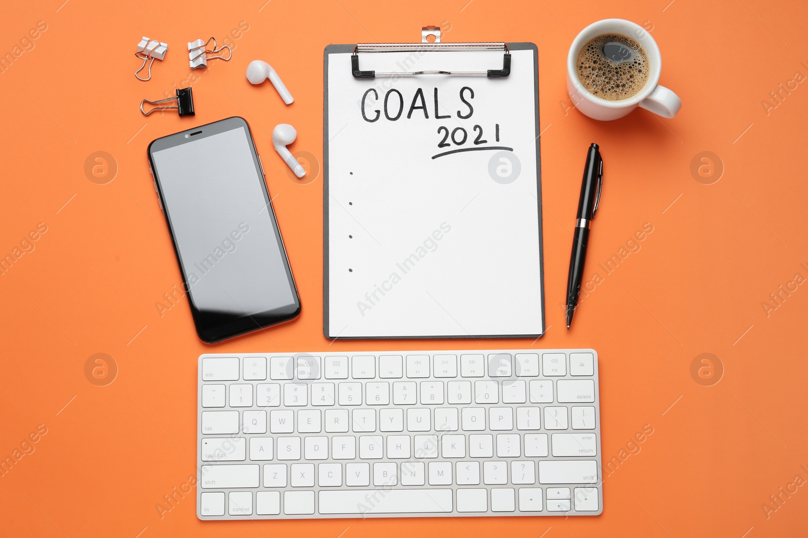 Photo of Paper with inscription 2021 Goals, new year items. Objects on orange background, flat lay