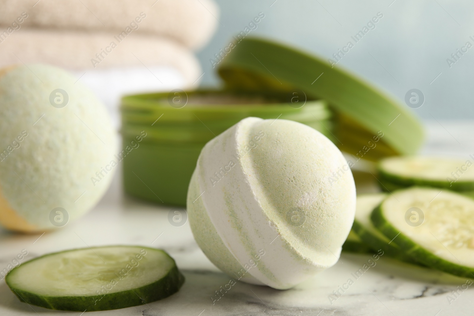 Photo of Bath bomb and cucumber slices on marble table