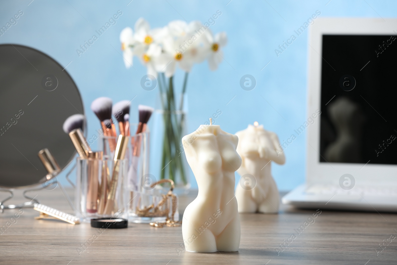 Photo of Beautiful female body shaped candle on wooden table indoors