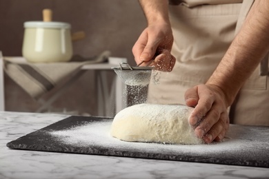 Photo of Male baker preparing bread dough at table, closeup