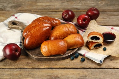 Photo of Delicious baked patties, jam, apples and blueberries on wooden table