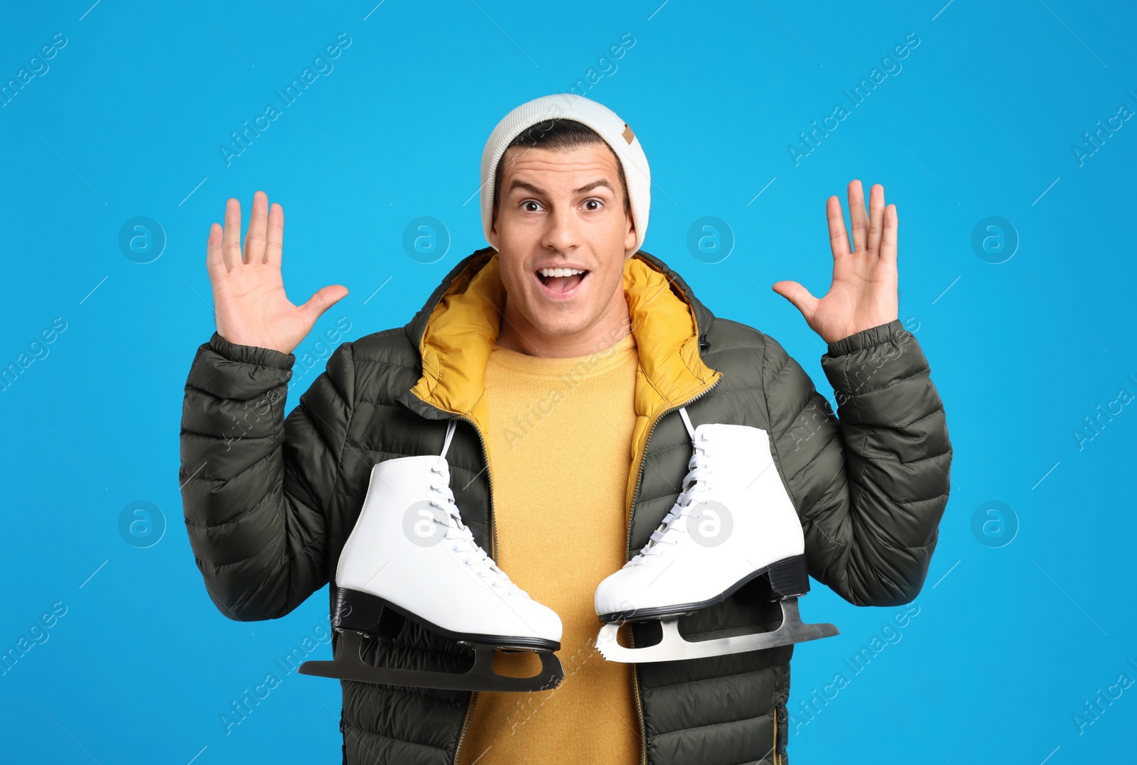 Photo of Emotional man with ice skates on light blue background