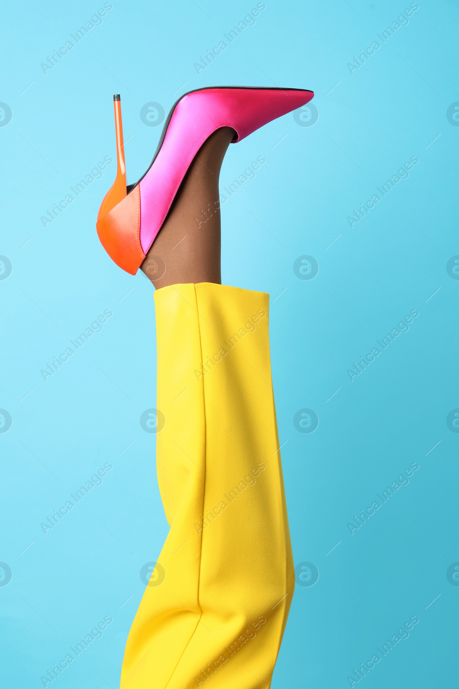 Photo of Woman wearing high heel shoe on light blue background, closeup