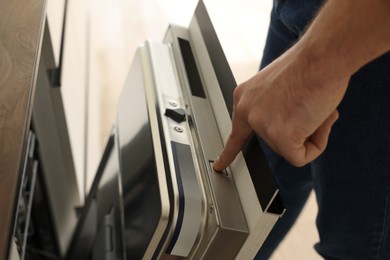 Man pushing button on dishwasher's door indoors, closeup