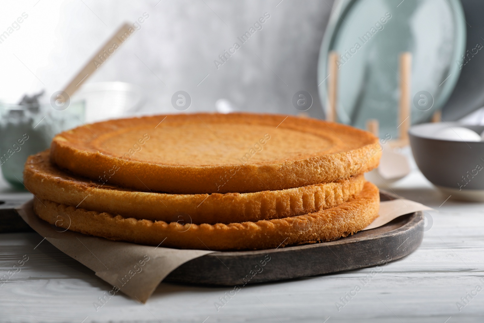 Photo of Delicious homemade sponge cakes and ingredients on white wooden table, closeup