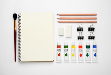 Composition with sketchbook and drawing tools on white background, top view