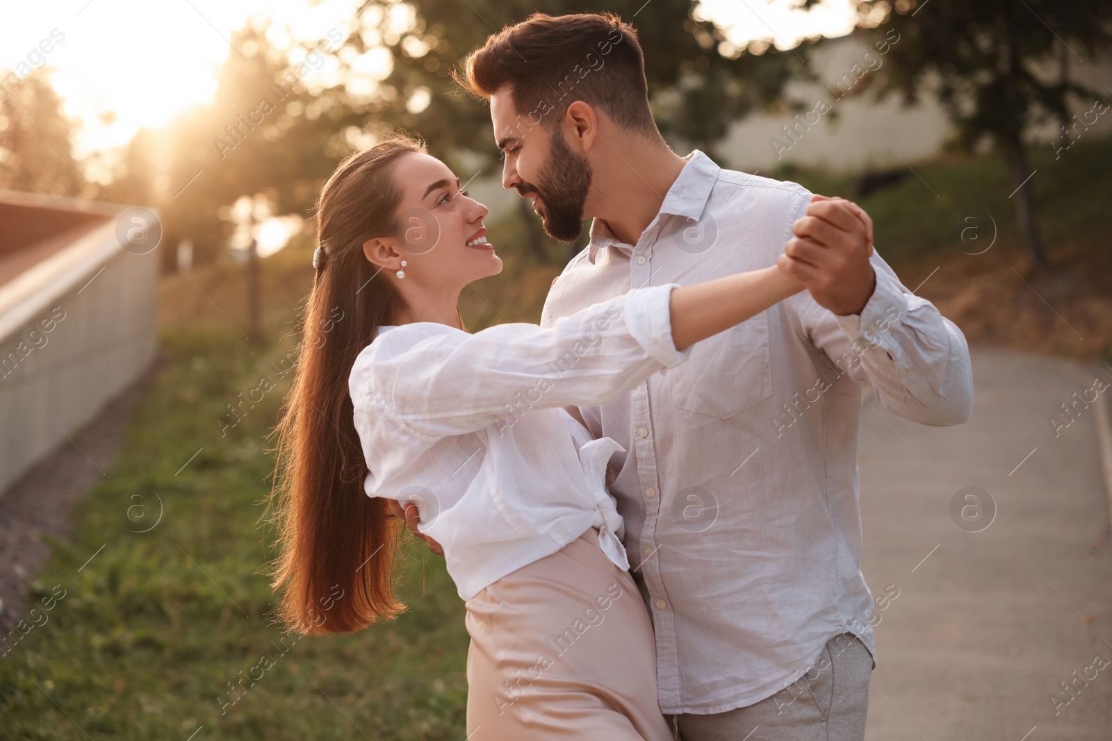 Photo of Lovely couple dancing together outdoors at sunset