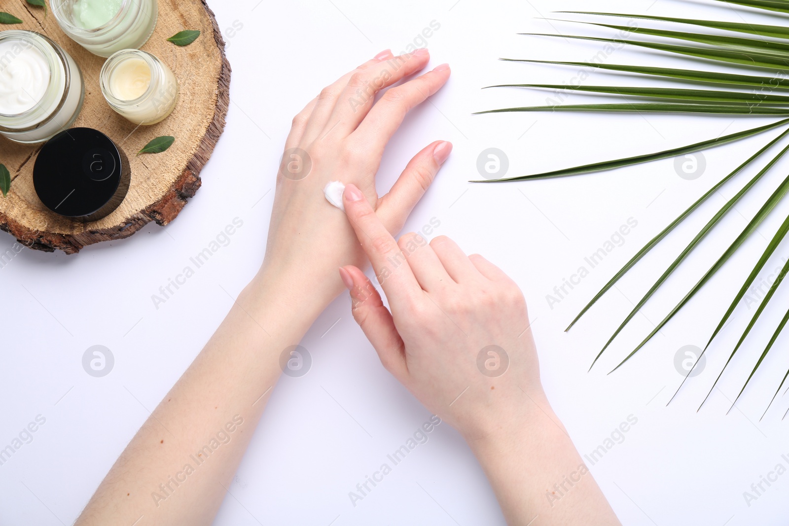 Photo of Woman applying hand cream on white background, top view