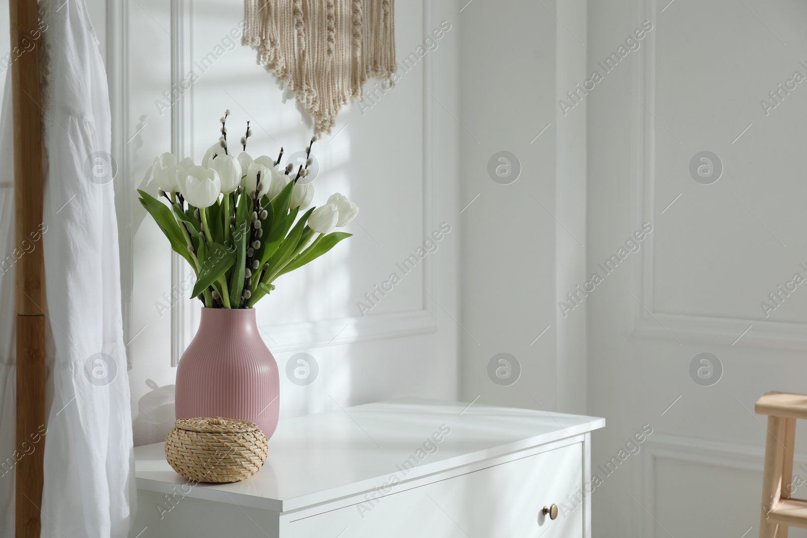 Photo of Beautiful bouquet of willow branches and tulips in vase indoors, space for text