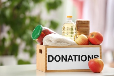 Photo of Donation box with food products on table indoors