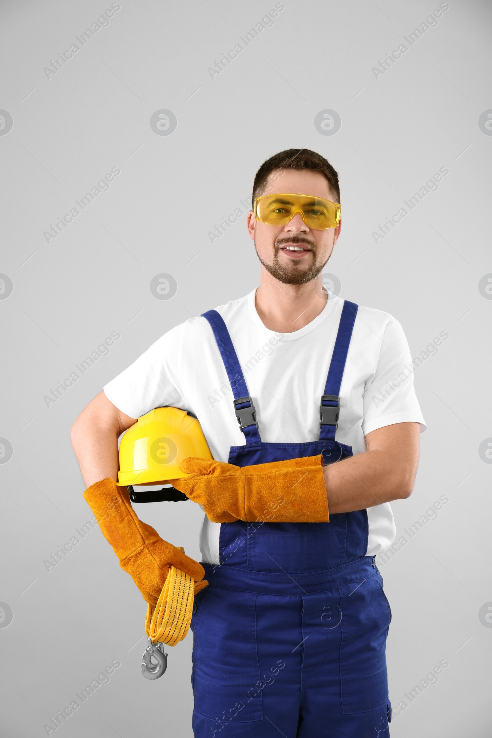 Photo of Male industrial worker in uniform on light background. Safety equipment