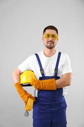 Photo of Male industrial worker in uniform on light background. Safety equipment