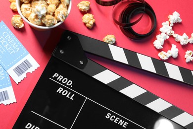 Photo of Flat lay composition with clapperboard and popcorn on red background