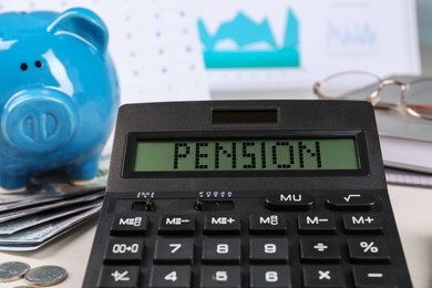 Image of Calculator with word Pension, money and piggy bank on table, closeup