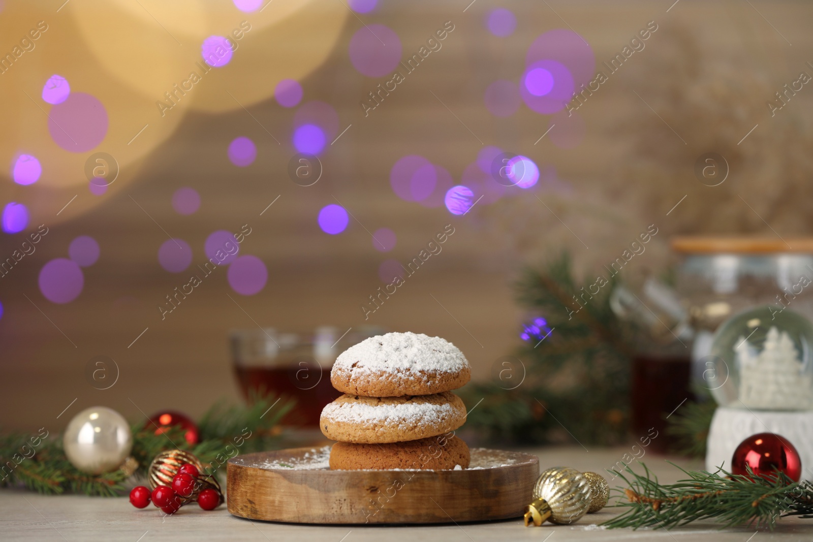 Photo of Delicious cookies and Christmas decor on wooden table against blurred festive lights