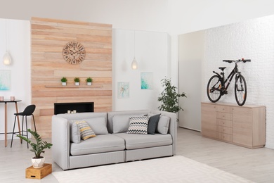 Photo of Bicycle on wooden chest of drawers in stylish room interior