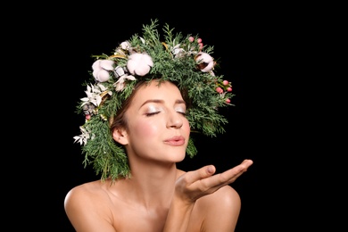 Young woman wearing wreath on black background