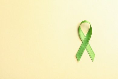 Photo of Green ribbon on color background, top view. Cancer awareness