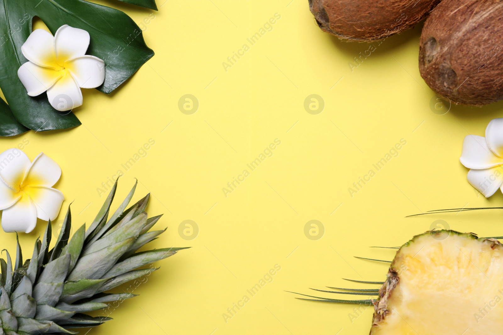 Photo of Flat lay composition with pineapples and coconuts on yellow background, space for text