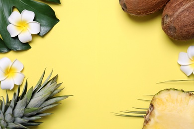 Flat lay composition with pineapples and coconuts on yellow background, space for text