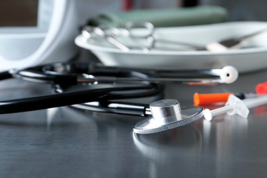 Stethoscope and syringes on grey table. Medical objects