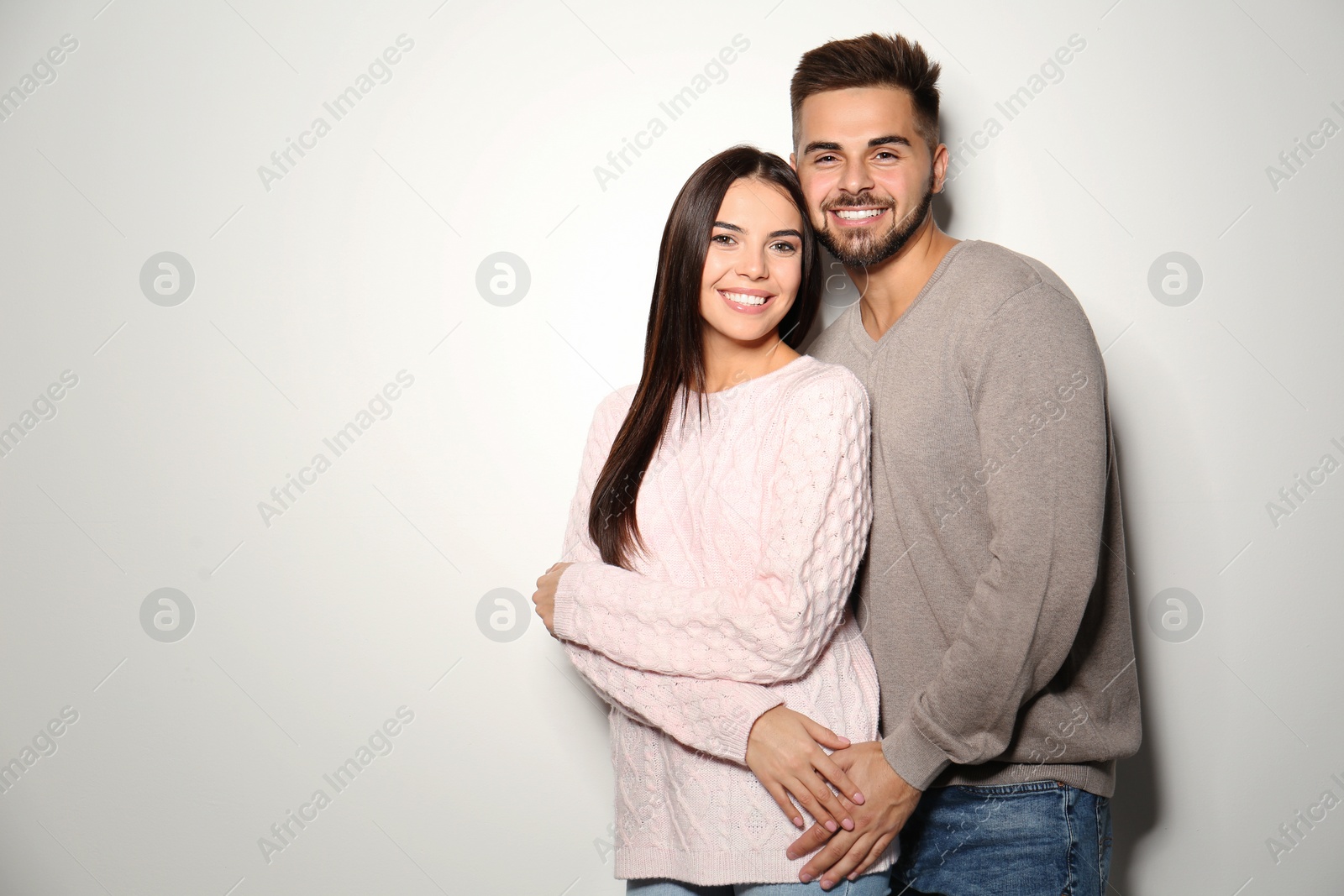 Image of Lovely couple in warm sweaters on light background. Space for text