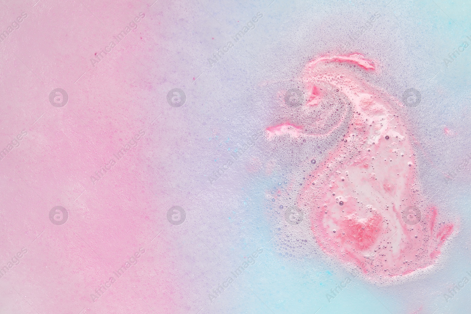 Photo of Colorful foam after dissolving bath bomb in water, closeup