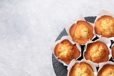 Delicious sweet muffins on light grey textured table, top view. Space for text