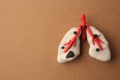 Photo of Human lungs made of plasticine on light brown background, top view and space for text. Respiratory disease concept