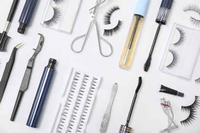 Flat lay composition with false eyelashes and cosmetic tools on white background