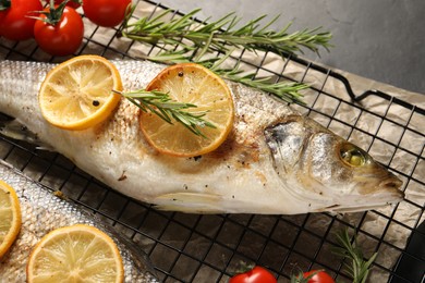 Photo of Baked fish with tomatoes, rosemary and lemon on black table, top view