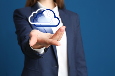 Image of Woman holding virtual clouds icon on blue background, closeup of hand. Data storage concept
