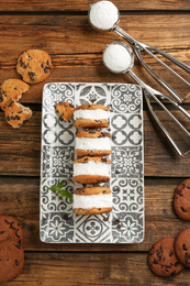 Photo of Sweet delicious ice cream cookie sandwiches on wooden table, flat lay