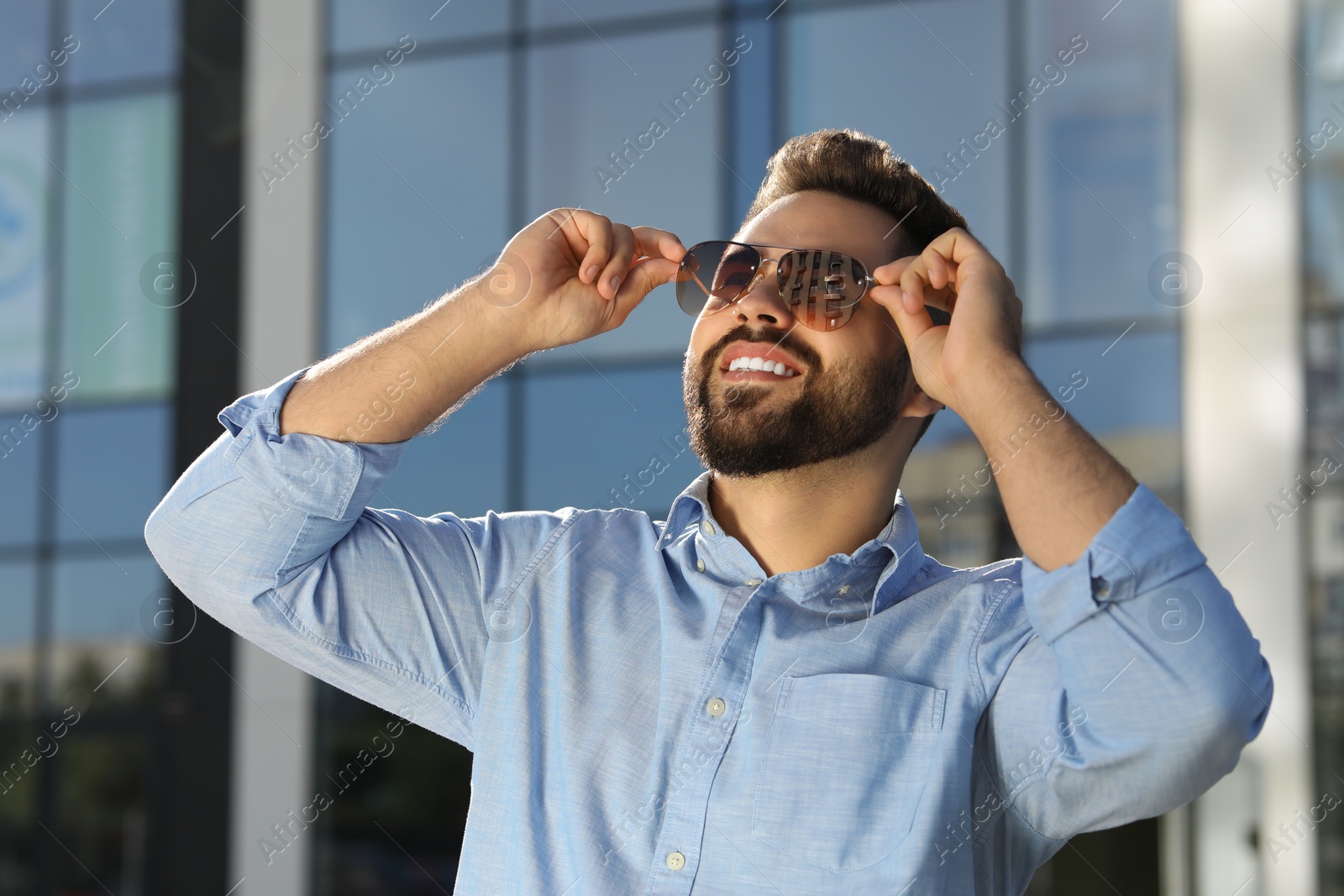 Photo of Handsome smiling man in sunglasses outdoors on sunny day