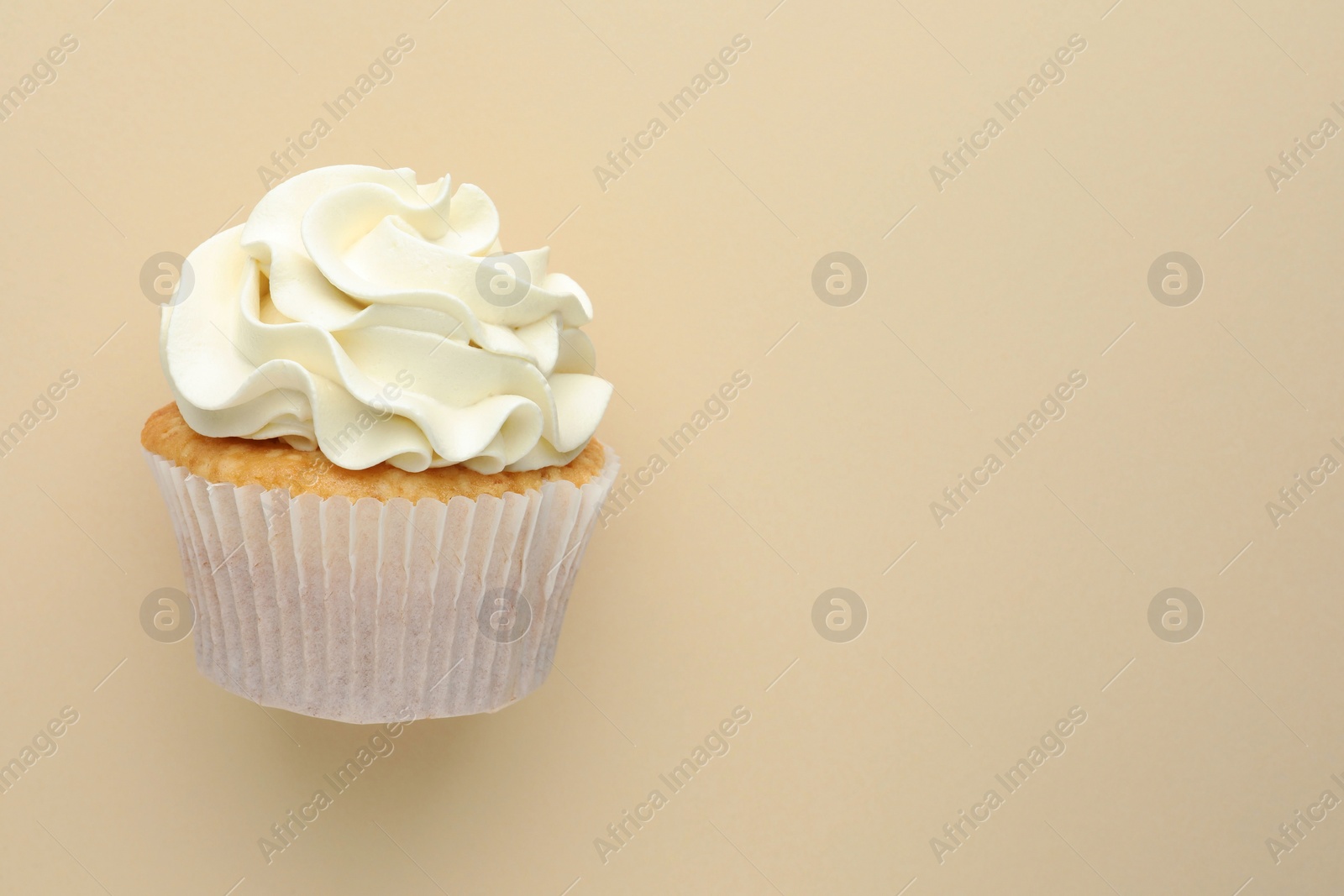 Photo of Tasty vanilla cupcake with cream on beige background, top view. Space for text